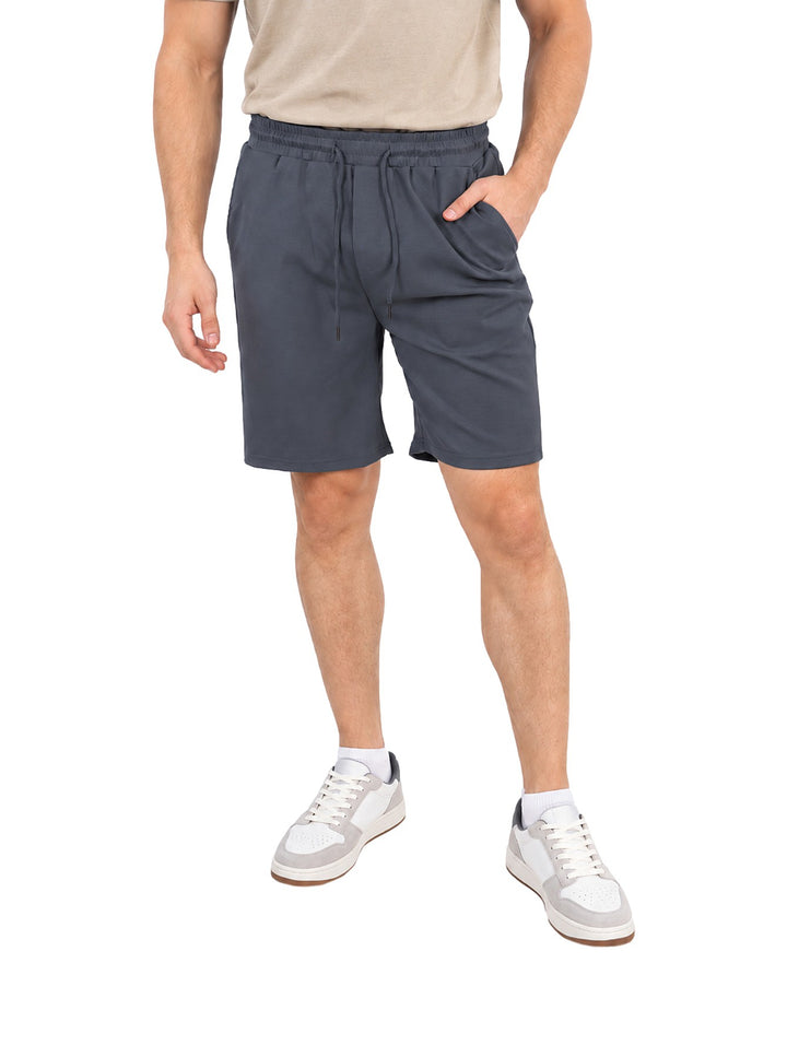Hombre vistiendo un short azul con jareta y cintura elástica, estilo casual.