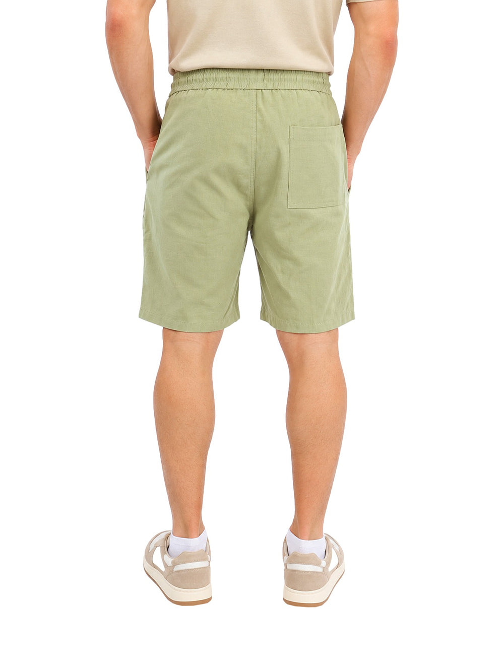 Hombre vistiendo short corto color verde con jareta en la cintura y calzado casual blanco.