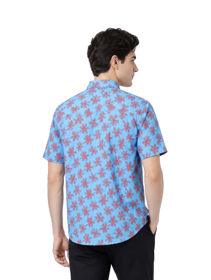 Hombre vistiendo camisa azul de manga corta con estampado floral rojo.
