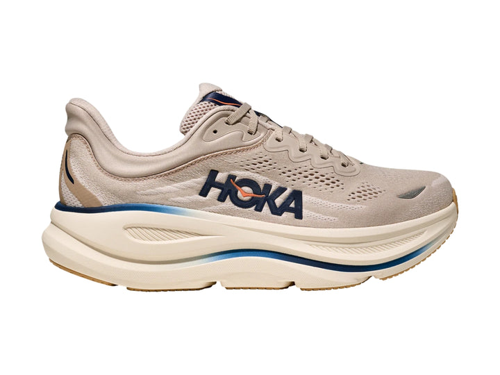Tenis deportivos HOKA Bondi 9 en color beige con detalles en azul y suela blanca ancha.