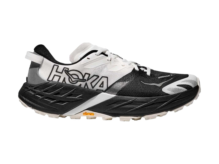 Tenis HOKA Speedgoat 7 en colores blanco y negro con suela robusta para trail running.