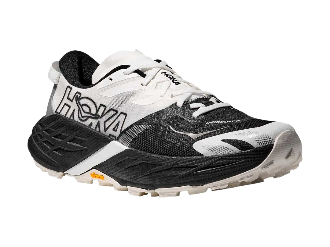 Tenis HOKA Speedgoat 7 en colores blanco y negro con suela robusta para trail running.