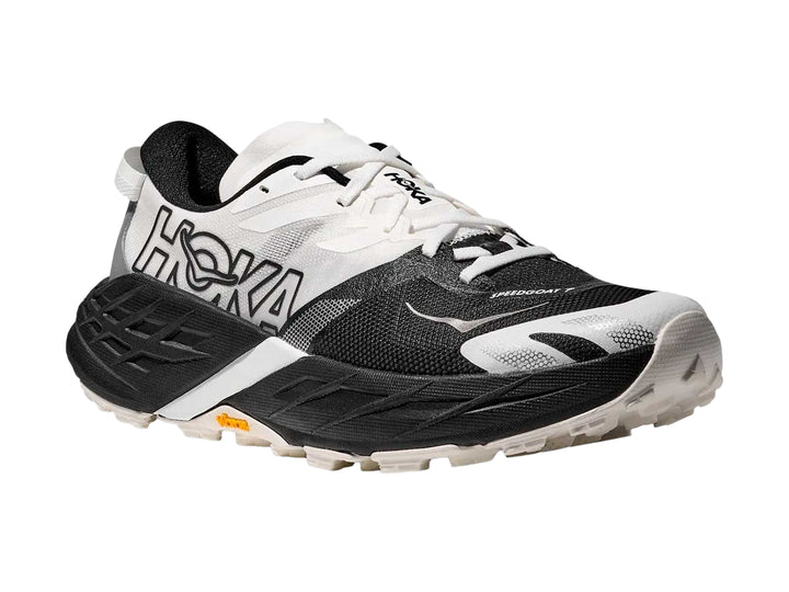 Tenis HOKA Speedgoat 7 en colores blanco y negro con suela robusta para trail running.