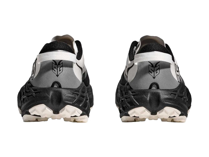 Tenis HOKA Speedgoat 7 en colores blanco y negro con suela robusta para trail running.