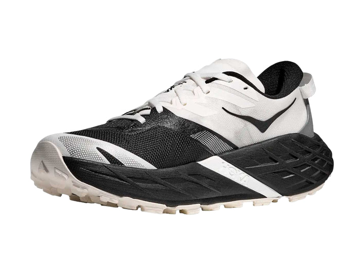 Tenis HOKA Speedgoat 7 en colores blanco y negro con suela robusta para trail running.