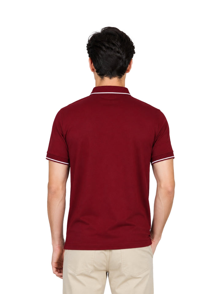Hombre vistiendo playera polo color tinto con detalles blancos en el cuello y los bordes de las mangas.