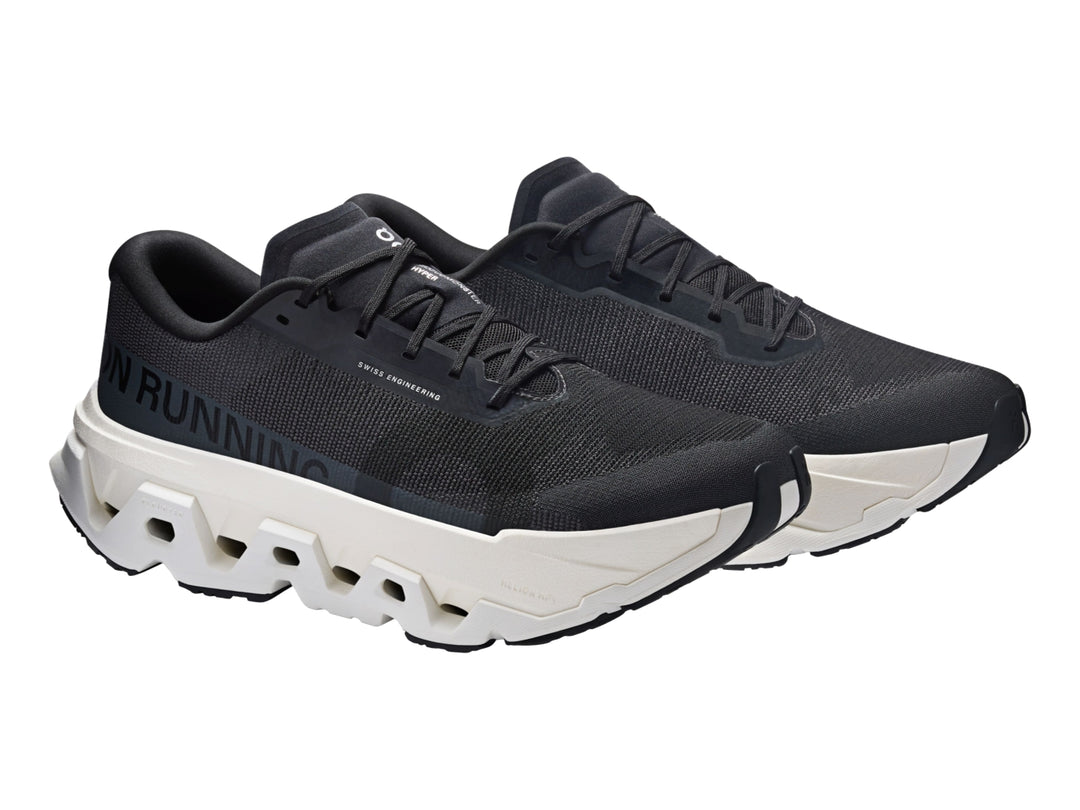 Tenis deportivos On Cloudmonster Hyper color negro con suela gruesa en tono marfil.