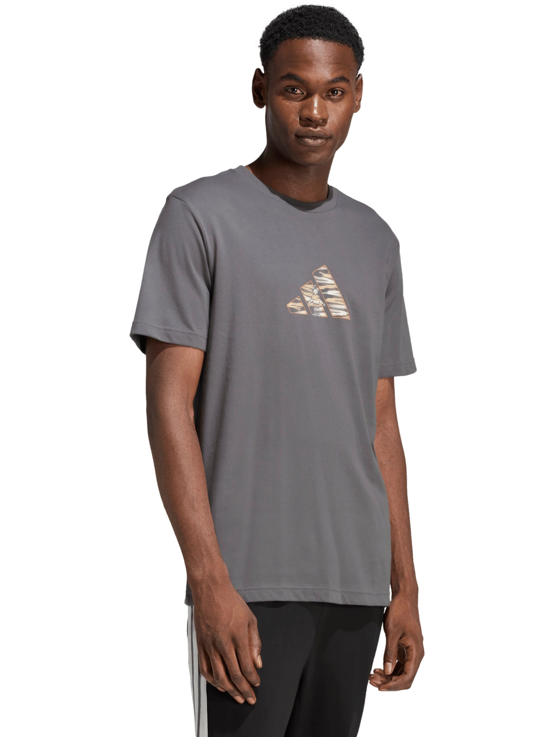 Hombre vistiendo playera Adidas color gris con logotipo gráfico camuflaje en el pecho.