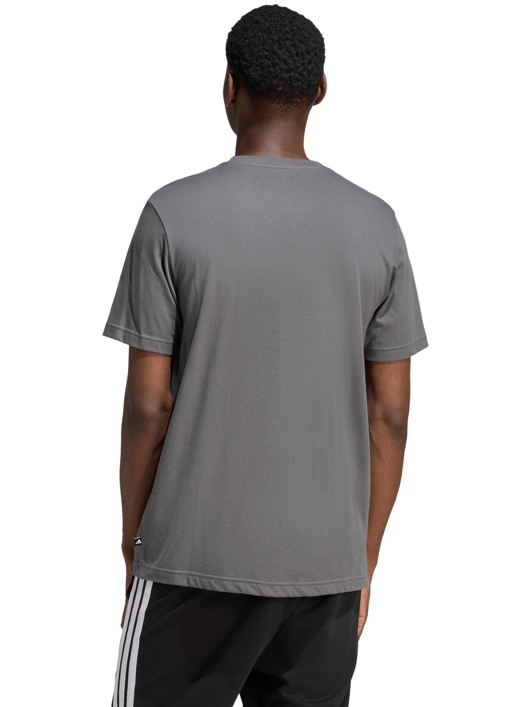 Hombre vistiendo playera Adidas color gris con logotipo gráfico camuflaje en el pecho.