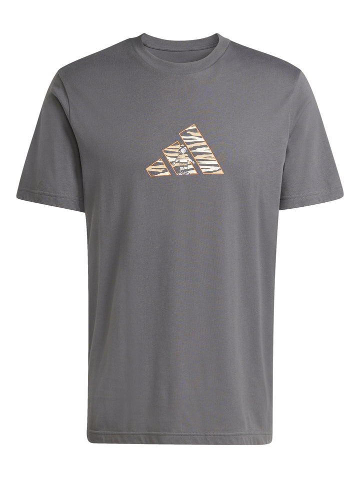 Hombre vistiendo playera Adidas color gris con logotipo gráfico camuflaje en el pecho.