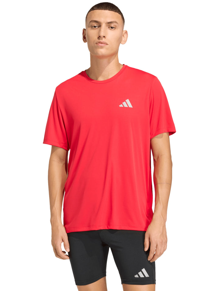 Hombre vistiendo playera deportiva roja de manga corta marca Adidas.
