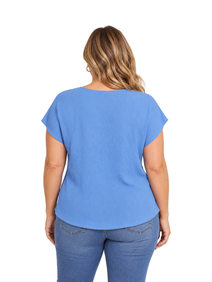 Mujer vistiendo blusa azul de marca Lissa You con cuello en V y textura rugosa, combinada con jeans azules.