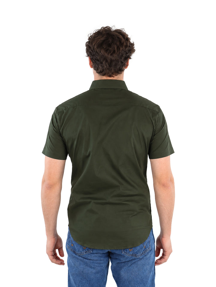 Hombre vistiendo una camisa de manga corta color verde militar y pantalones azules.
