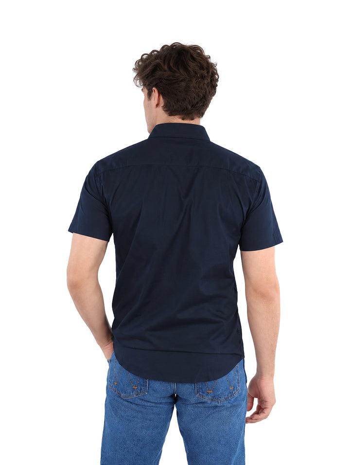 Hombre vistiendo una camisa negra de manga corta y pantalones vaqueros azules.