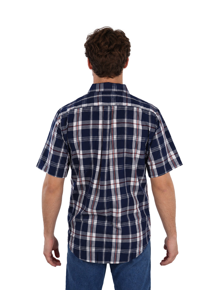 Hombre vistiendo camisa de manga corta con estampado de cuadros en colores marino, blanco y rojo.