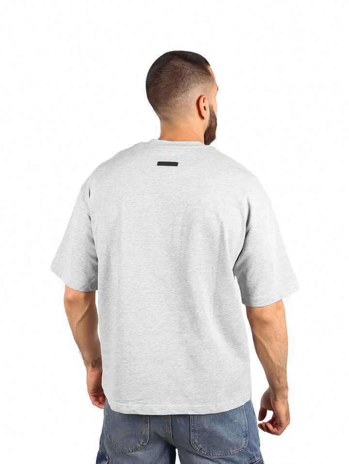 Hombre vistiendo una playera básica de color gris con cuello redondo y manga corta.