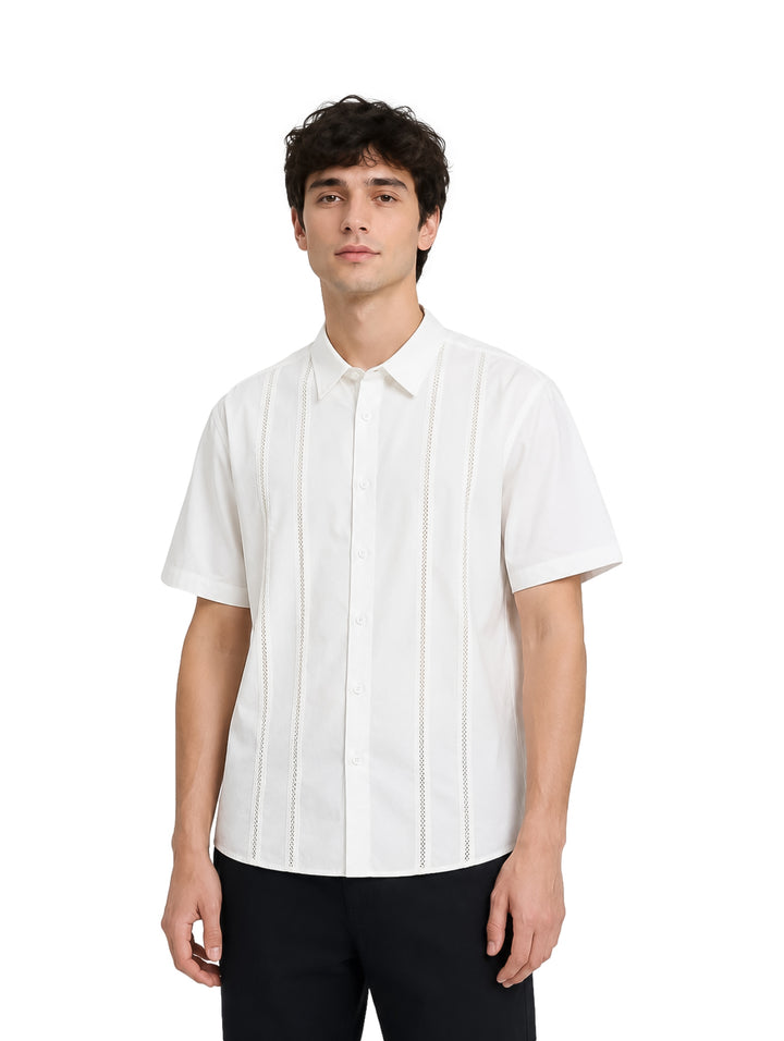 Hombre vistiendo camisa blanca de manga corta con detalles verticales y cuello, estilo elegante.