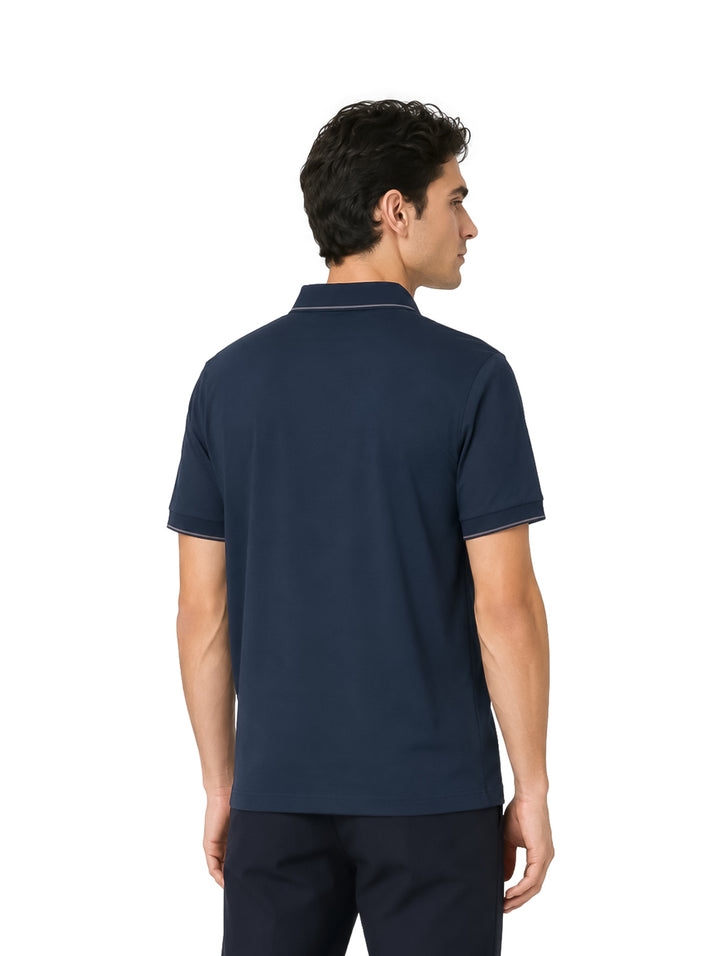 Hombre vistiendo playera polo color navy con detalles blancos en el cuello y bordes de las mangas.