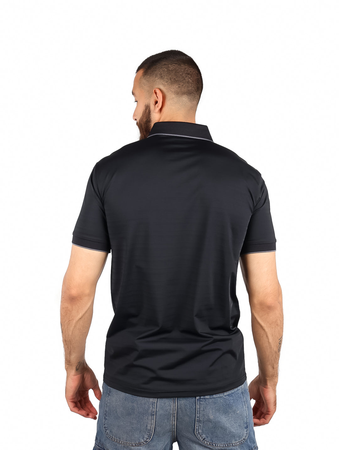 Hombre vistiendo una playera polo color negro de manga corta con detalles blancos en el cuello.