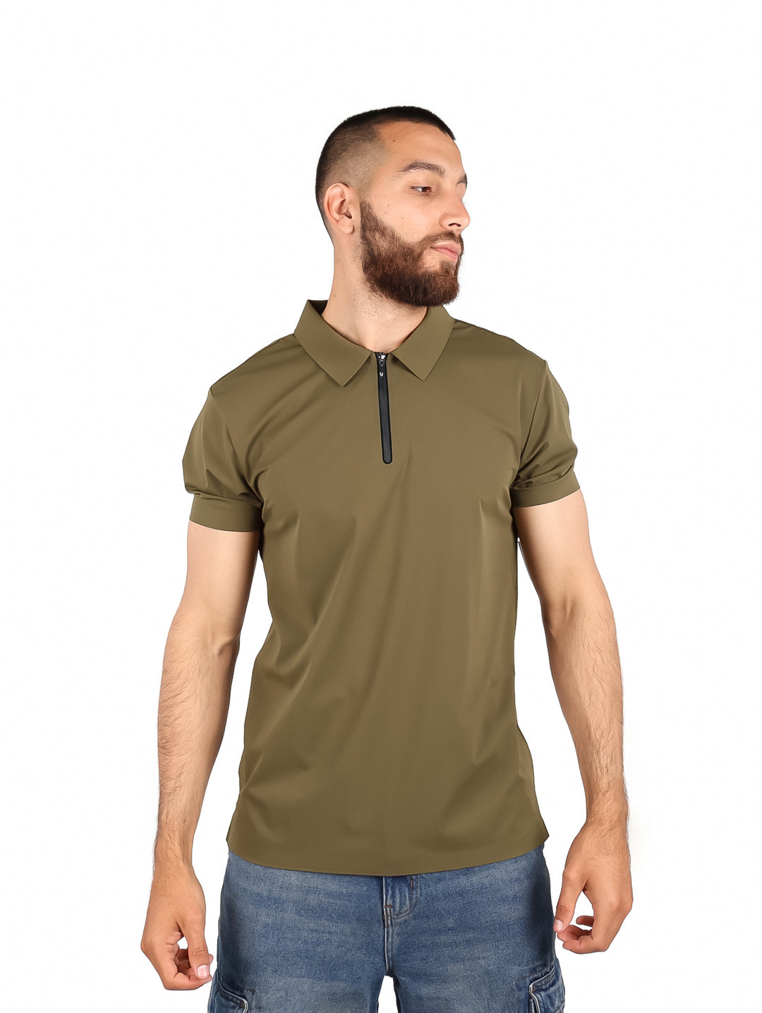 Hombre usando playera polo color olivo con cierre frontal y pantalones mezclilla azules.