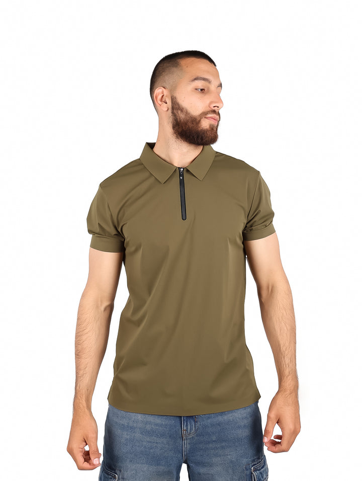 Hombre usando playera polo color olivo con cierre frontal y pantalones mezclilla azules.