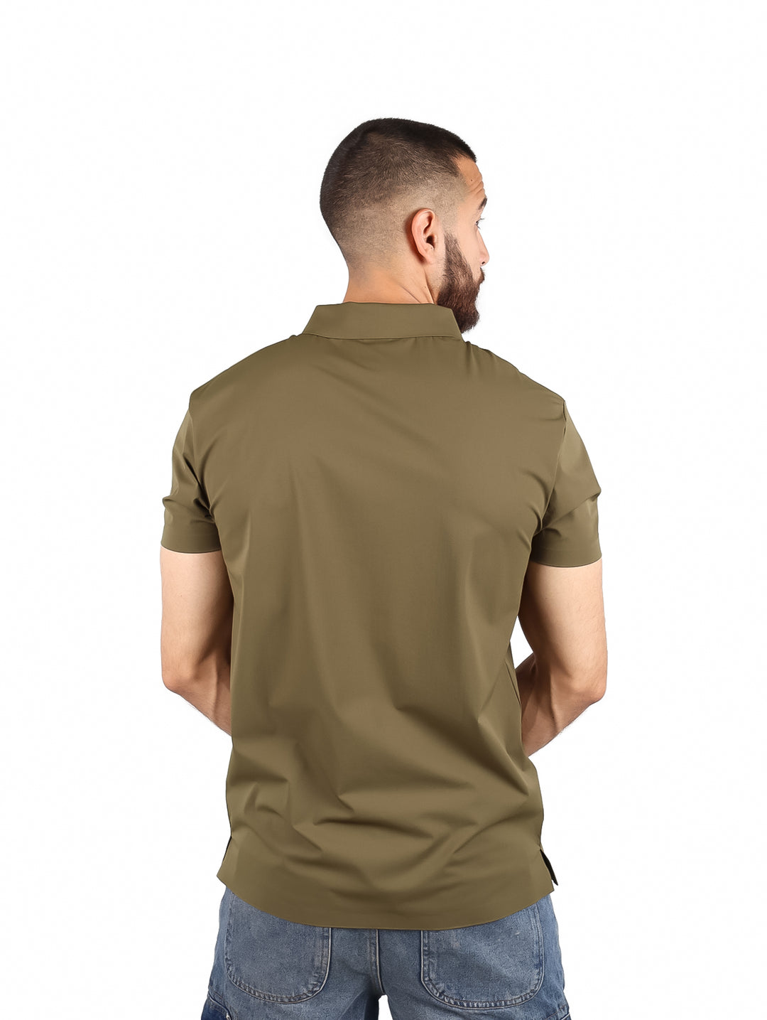 Hombre usando playera polo color olivo con cierre frontal y pantalones mezclilla azules.