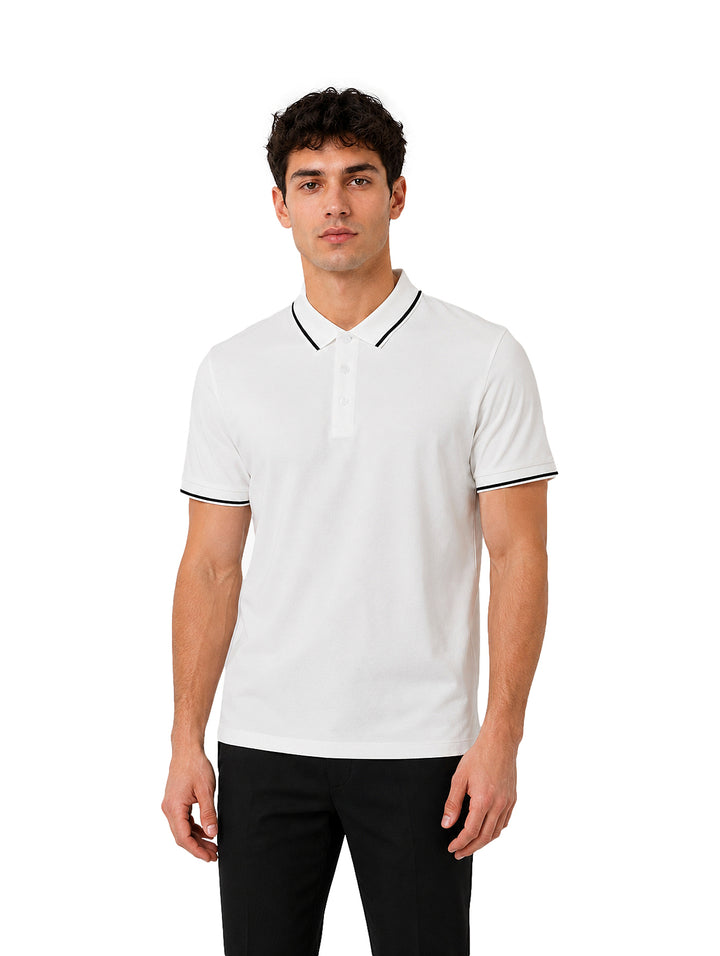 Hombre vistiendo playera polo blanca con detalles negros en el cuello y los bordes de las mangas.
