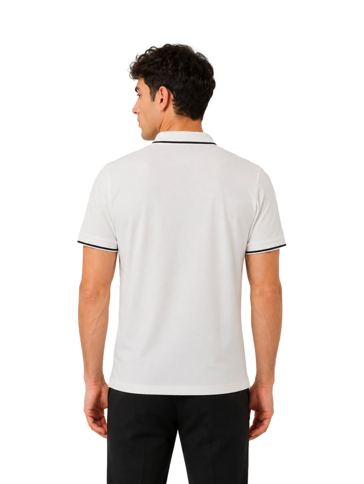 Hombre vistiendo playera polo blanca con detalles negros en el cuello y los bordes de las mangas.