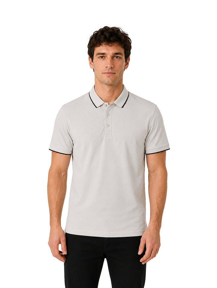 Hombre vistiendo playera polo color bone con detalles negros en el cuello y los bordes de las mangas.