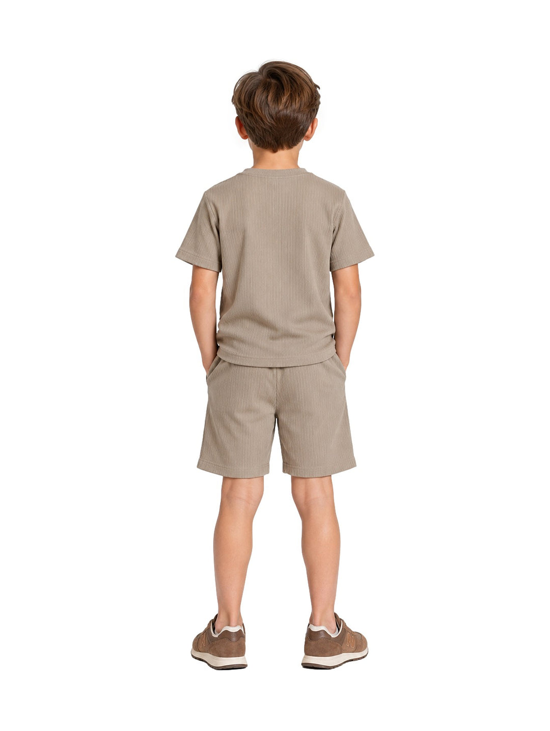 Niño vistiendo un conjunto de camiseta y short en color verde claro con textura acanalada y tenis marrones.