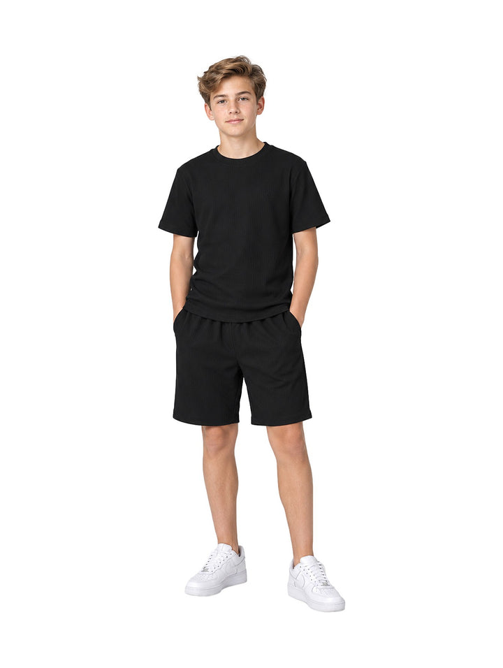 Niño vistiendo conjunto Atok negro compuesto por camiseta de manga corta y shorts a juego.