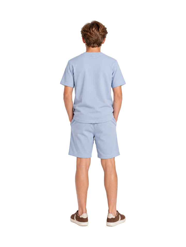 Niño vistiendo un conjunto de camiseta y shorts en color azul claro de la marca ATOK.