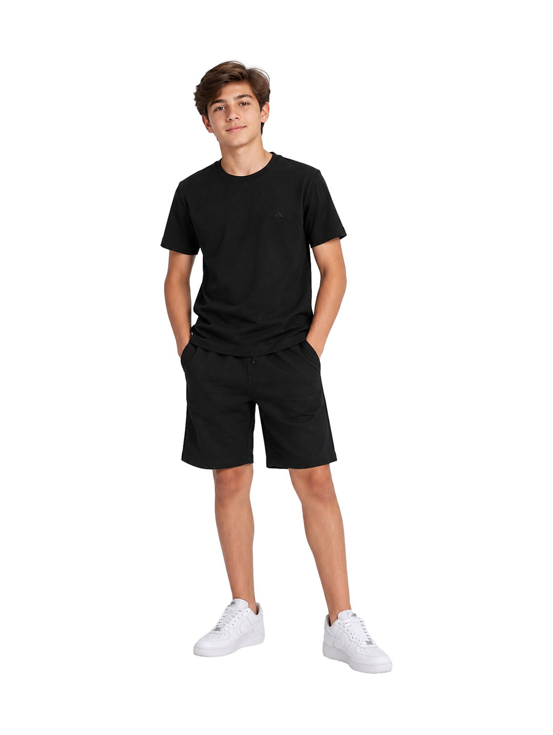 Niño vistiendo un conjunto de camiseta y shorts color negro de la marca ATOK con tenis blancos.