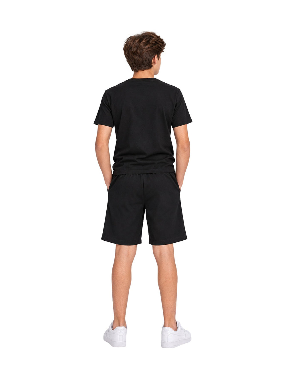 Niño vistiendo un conjunto de camiseta y shorts color negro de la marca ATOK con tenis blancos.