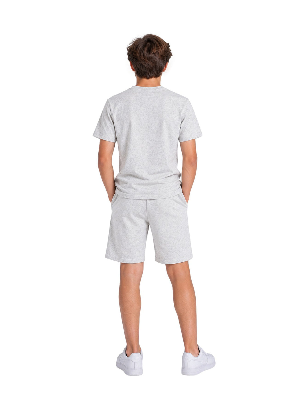 Niño vistiendo un conjunto casual de camiseta y short en color gris claro con tenis blancos.