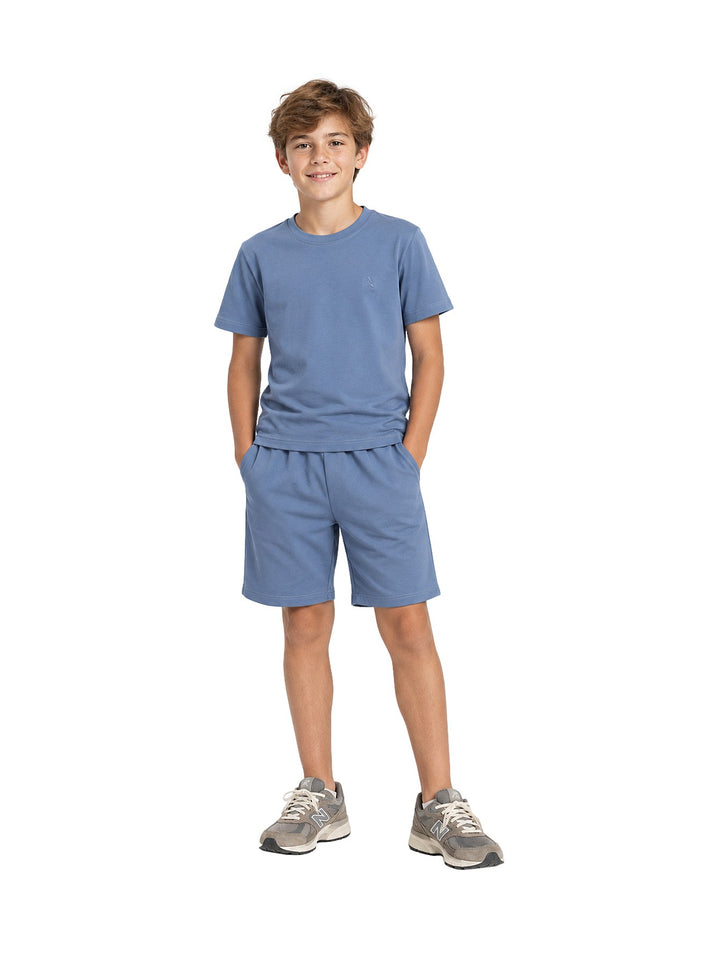 Niño vistiendo un conjunto de camiseta y shorts color azul denim de la marca ATOK.