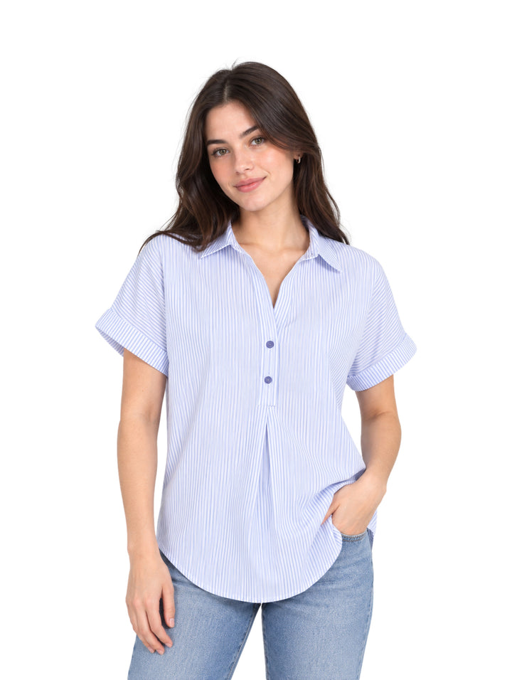 Mujer vistiendo una camisa de rayas azules y blancas de manga corta y pantalones vaqueros.