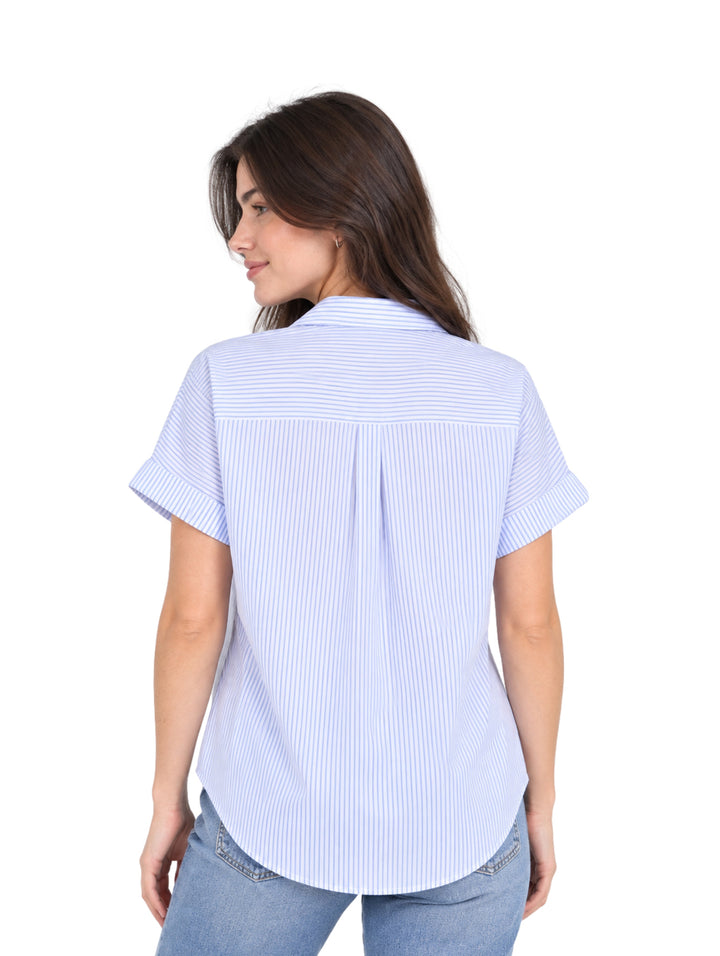 Mujer vistiendo una camisa de rayas azules y blancas de manga corta y pantalones vaqueros.