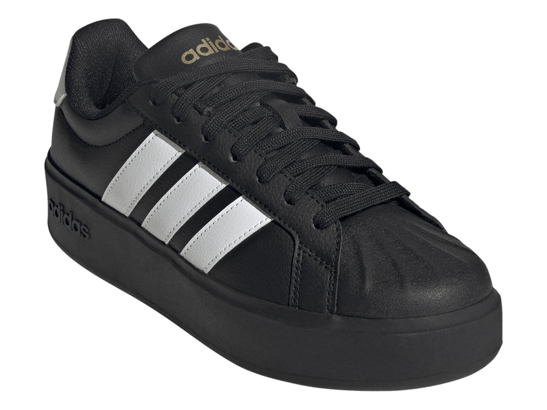 Tenis Adidas negros con franjas blancas laterales y suela de plataforma gruesa.