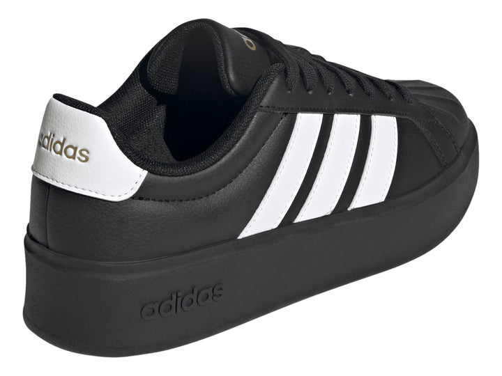 Tenis Adidas negros con franjas blancas laterales y suela de plataforma gruesa.