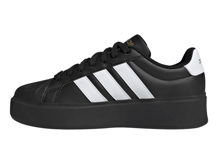 Tenis Adidas negros con franjas blancas laterales y suela de plataforma gruesa.