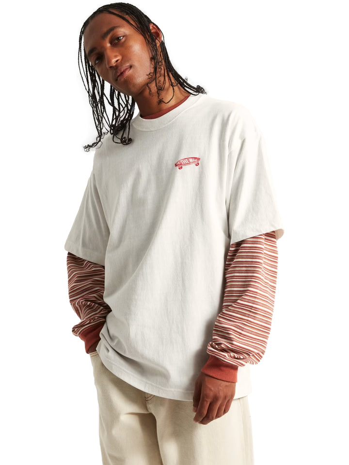Hombre vistiendo una camiseta blanca de manga corta sobre una camiseta a rayas rojas y blancas de manga larga.