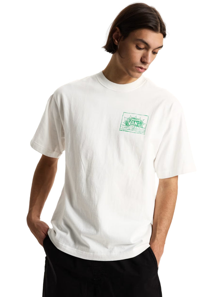 Hombre vistiendo una camiseta blanca de manga corta de la marca Vans con un pequeño gráfico verde en el pecho.