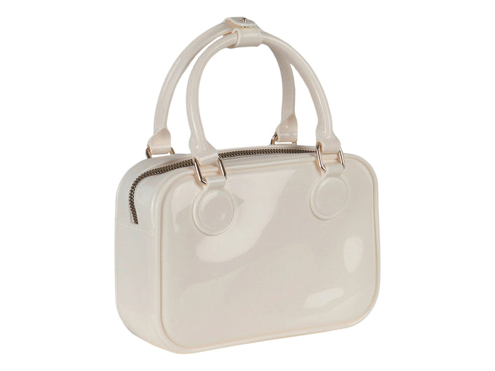Bolsa de mano color latte con acabado brillante y detalles metálicos dorados.