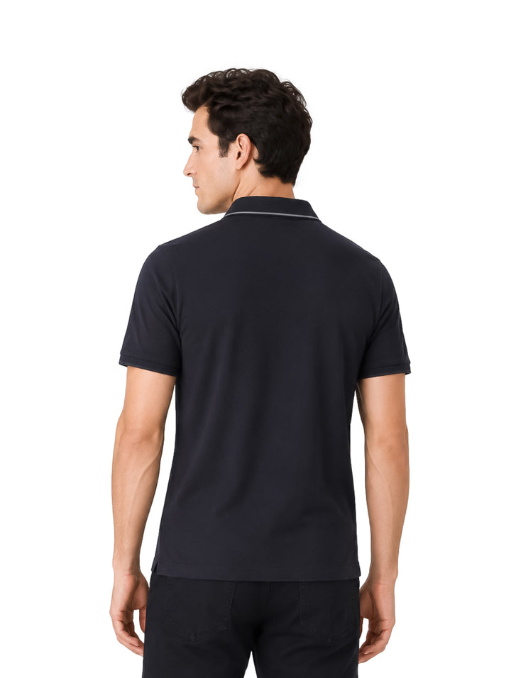 Hombre vistiendo una playera polo color negro de manga corta con detalle blanco en el cuello.