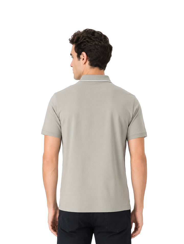 Hombre vistiendo playera polo color olive de manga corta con detalle blanco en el cuello.