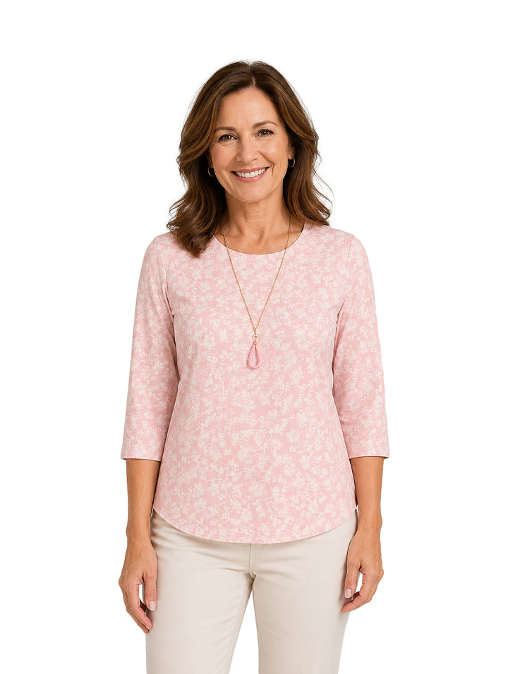 Mujer vistiendo blusa rosa con estampado floral y collar largo.
