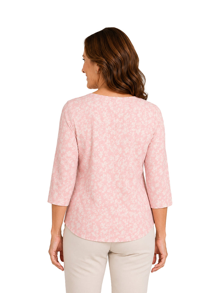 Mujer vistiendo blusa rosa con estampado floral y collar largo.