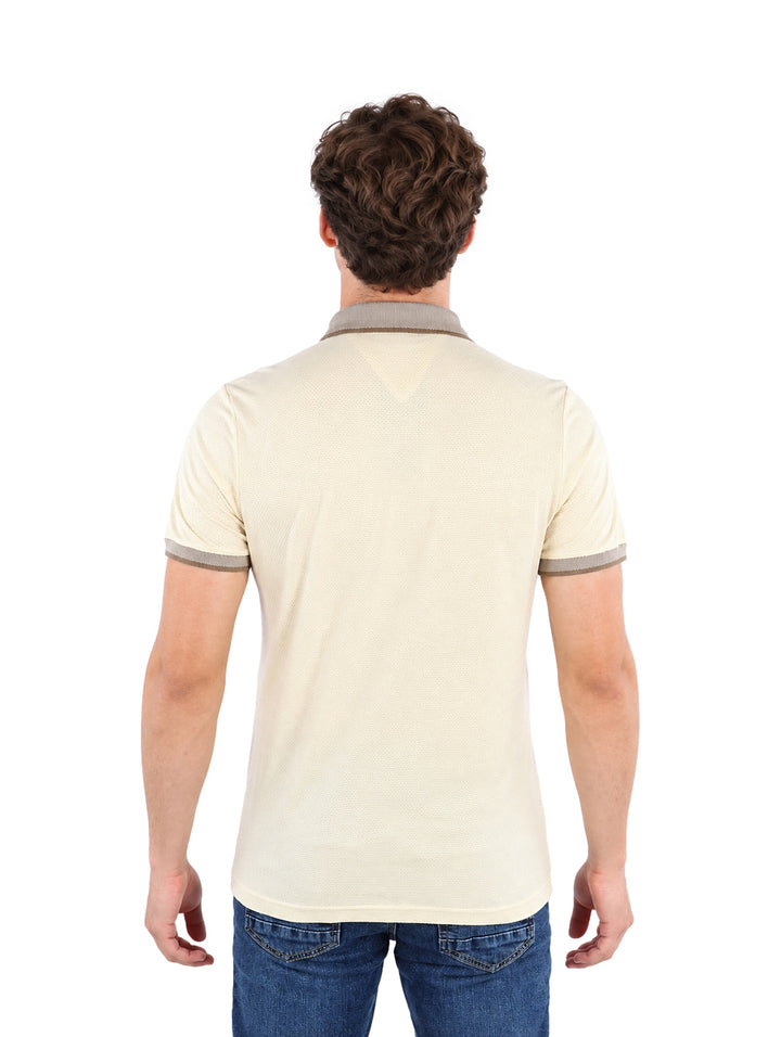 Hombre vistiendo una playera polo color beige de manga corta con detalles en el cuello y mangas.