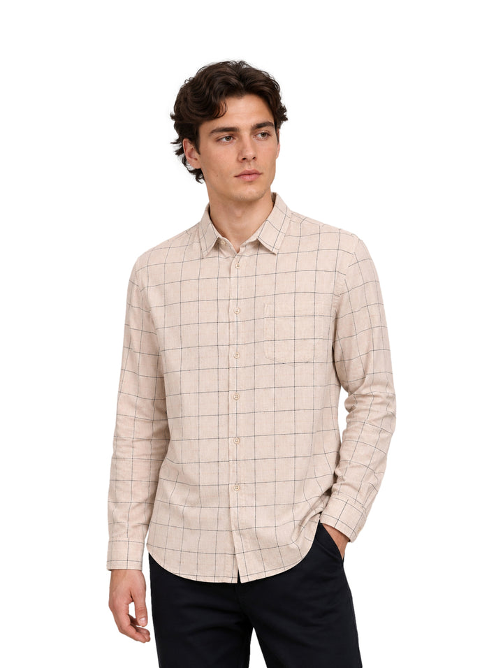Hombre vistiendo camisa beige de manga larga con estampado de cuadros negros.